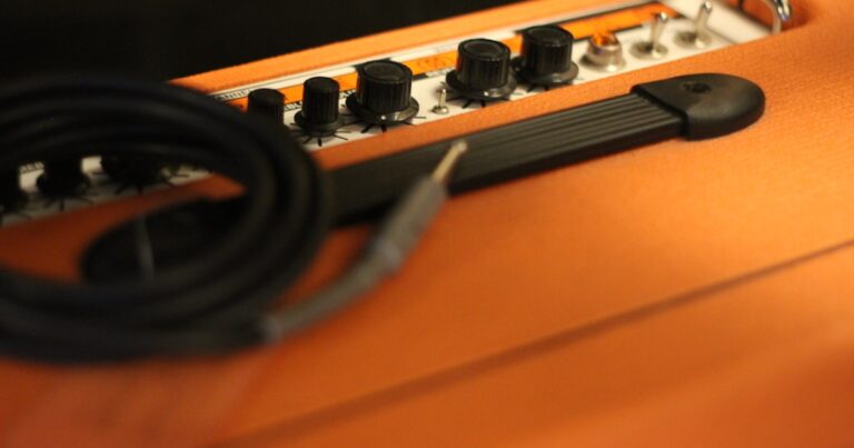 Cabo de instrumento P10 enrolado sobre um amplificador de guitarra laranja